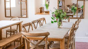A dining area with a long wooden table, multiple chairs, and a vase with flowers.