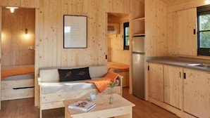L’intérieur d’un chalet en bois, avec un canapé, une petite table et un coin cuisine.