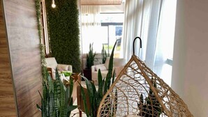 Un interior moderno con un sillón colgante, plantas en macetas y una pared verde.