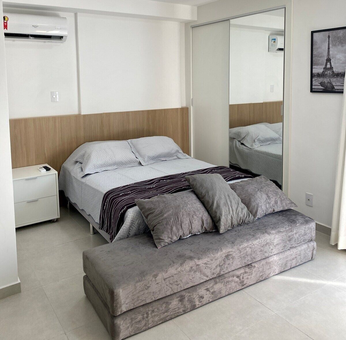 A modern bedroom with a bed, bedside table, and a large mirror.