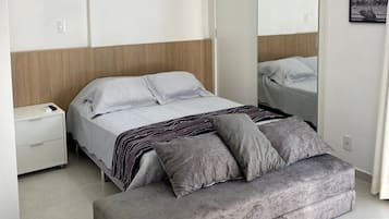 A modern bedroom with a bed, bedside table, and a large mirror.