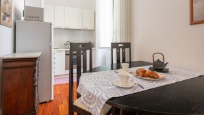 A dining area with a table set for two, a kettle, and a plate of croissants. - Casa Novecento Prati (Roma)