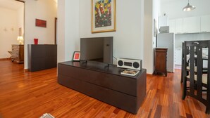 A modern living room with a flat-screen TV, a radio, and a wooden coffee table. - Casa Novecento Prati (Roma)