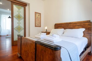 Un dormitorio con una cama de madera, una mesita de noche con lámpara y una pared con un panel decorativo y un cuadro enmarcado.