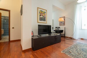 Un salon moderne avec un téléviseur à écran plat, un meuble en bois foncé, une lampe sur pied et un tapis à motifs.