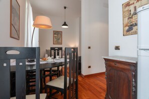 Uma área de refeições com uma mesa, cadeiras, um abajur e um armário.