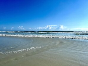 Enjoy a serene beach experience with calm ocean waves and a wide open shoreline.