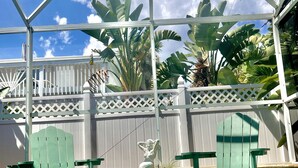 A swimming pool with a pink flamingo float, two green Adirondack chairs, and a mermaid statue. - Cozy beach home! Private pool, 2min walk to beach, walkable to restaurants/shops (New Smyrna Beach)
