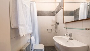 Ein Badezimmer mit Toilette, Dusche, Waschbecken und Spiegel.