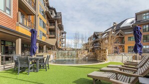Une cour avec une piscine, des espaces de détente en plein air et des immeubles à plusieurs étages dotés de balcons.
