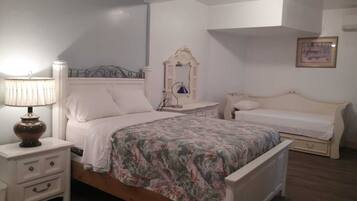 A bedroom with a bed, a nightstand, a dresser, a mirror, and a bedside table.