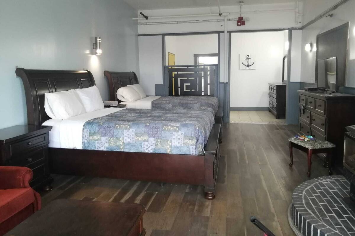 A hotel room with two beds, a TV, a desk, and a chair.