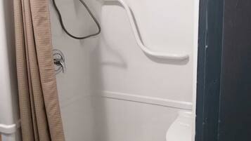 Un box de ducha con cortina color beige, pared blanca y suelo blanco.