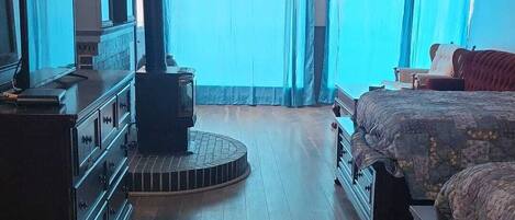 Een kamer met een bed, een dressoir en een houtkachel.
