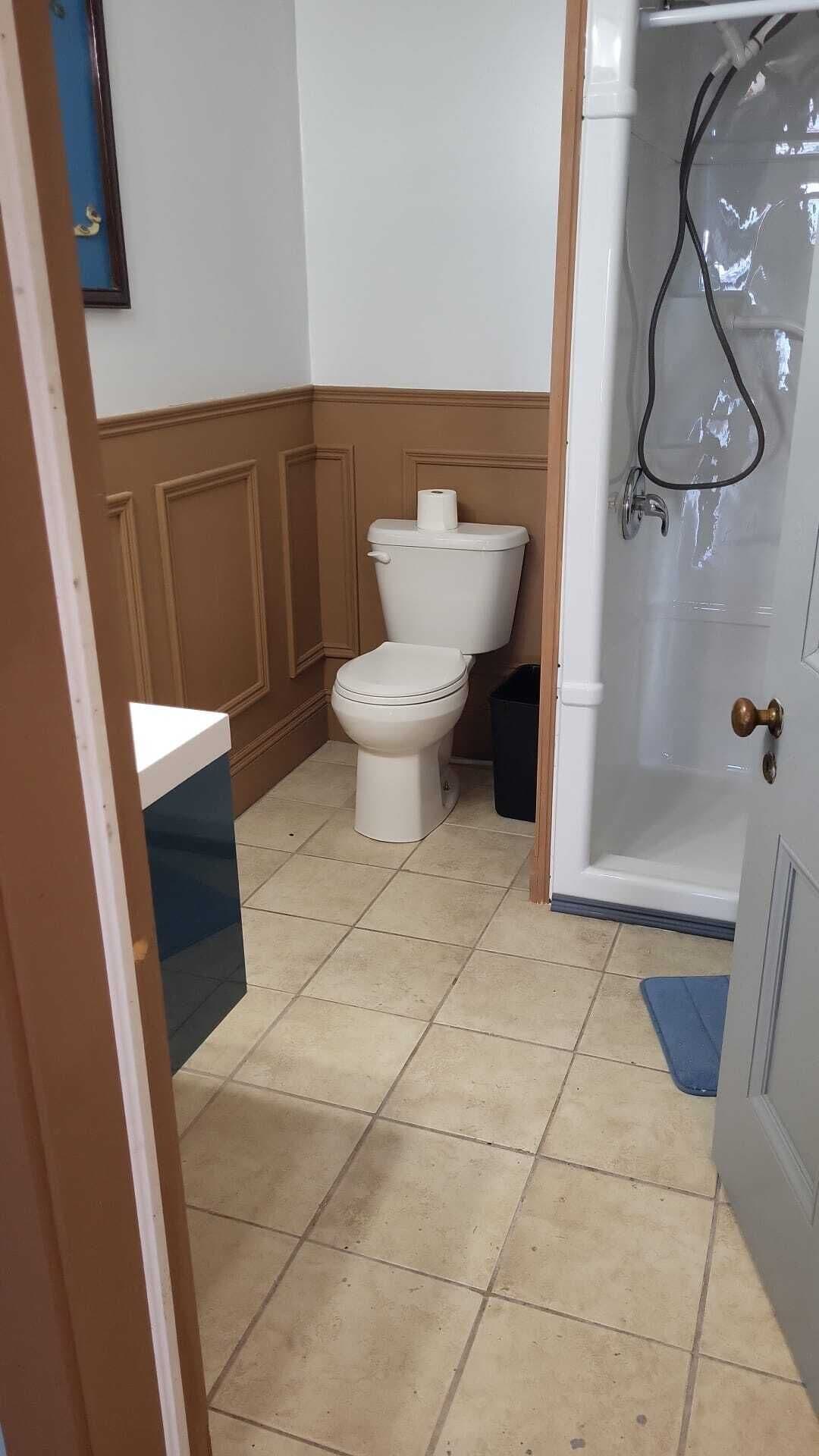 Une salle de bain comprenant des toilettes, un lavabo et un espace douche.