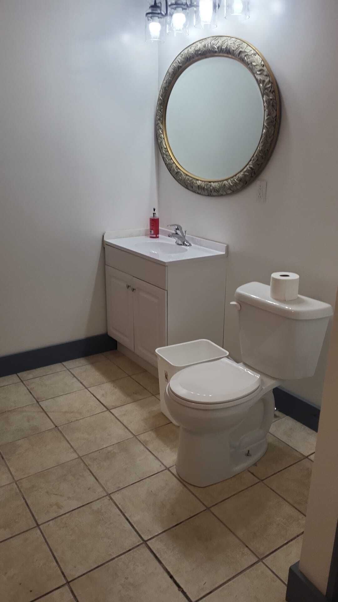 A bathroom with a toilet, sink, and a mirror.