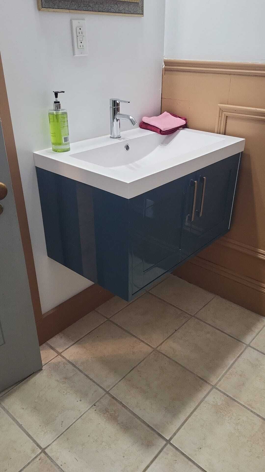 A bathroom with a white sink, a mirror, and a pink towel.