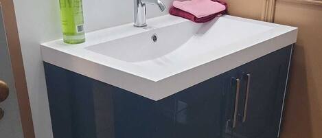 A bathroom with a white sink, a mirror, and a pink towel.