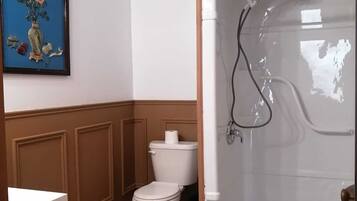 Un baño con inodoro, cabina de ducha y un cuadro en la pared.