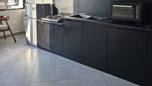 A modern kitchen with black cabinets, a built-in stove, and a microwave. - A cozy  romantic private self contained room in the bushes of kitovu kitende  (Kampala)