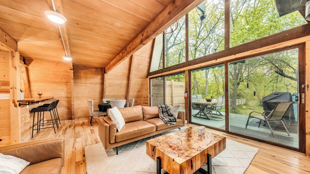 A wooden interior with a sofa, coffee table, and dining area. - Rustic Riverside A-Frame Retreat: Secluded Charm. (Racine)