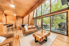 A wooden interior with a sofa, coffee table, and dining area. - Rustic Riverside A-Frame Retreat: Secluded Charm. (Racine)