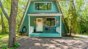 A two-story house with a porch, a door, and two windows. - Rustic Riverside A-Frame Retreat: Secluded Charm. (Racine)