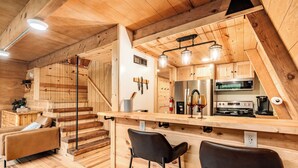 A wooden interior with a kitchen, bar area, and a staircase. - Rustic Riverside A-Frame Retreat: Secluded Charm. (Racine)