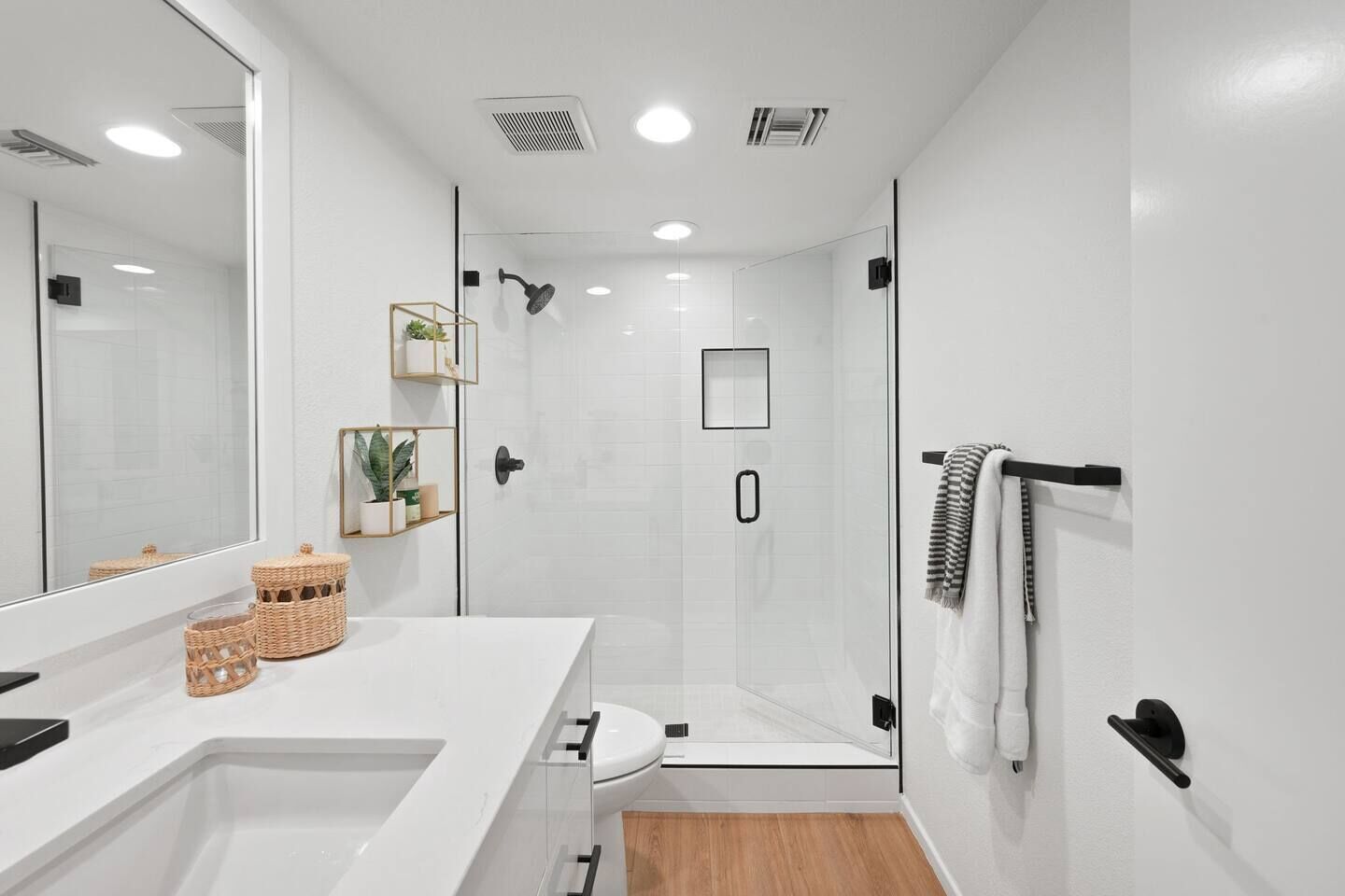 Casa de banho moderna com cabine de duche em vidro, lavatório branco e espelho grande.