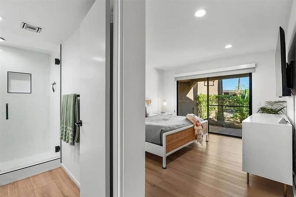 A modern bedroom with a bed, a TV, and a balcony with a view.