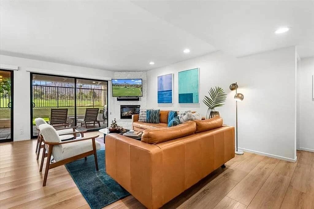 Una sala de estar moderna con un sofá de cuero, una mesa de centro de madera y un televisor montado en la pared.
