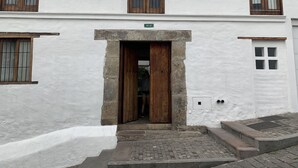 A white building with a wooden door and a small set of steps leading to the entrance. - Suite Centro Histórico (Quito)