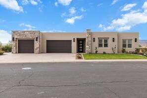 Une maison moderne à deux étages, dotée d’un garage, d’une porte d’entrée et d’un petit jardin à l’avant.