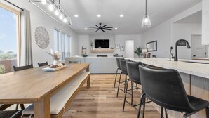 Een moderne keuken met een houten eettafel, barstoelen en een groot schiereiland.