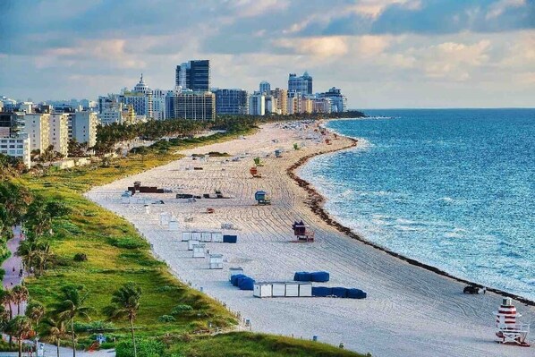 Enjoy the serene coastal views and stroll along the beach lined with beach umbrellas and sun loungers.