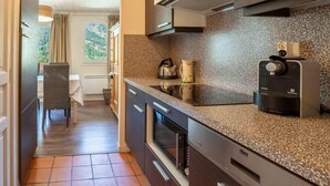 Una cocina moderna con armarios oscuros, horno empotrado y cafetera.