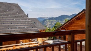 Een houten chalet met een schuin dak en uitzicht op bergen.