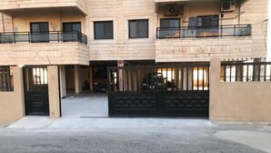 Ein mehrgeschossiges Gebäude mit geschlossenem Eingangsbereich, Balkonen und einem sichtbaren Garagenbereich.