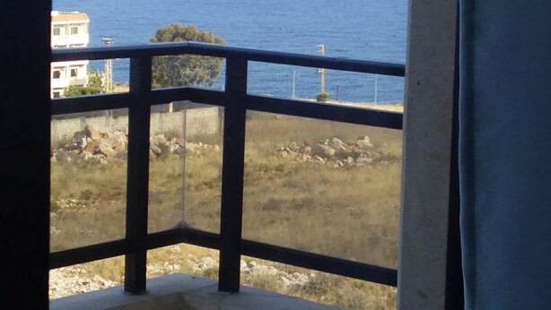 Ein Balkon mit Blick auf das Meer und eine felsige Landschaft.