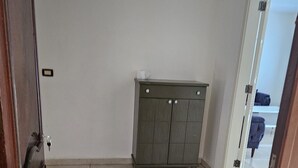 Ein Zimmer mit Fliesenboden, einer Holztür und einem grauen Schrank mit Schubladen.