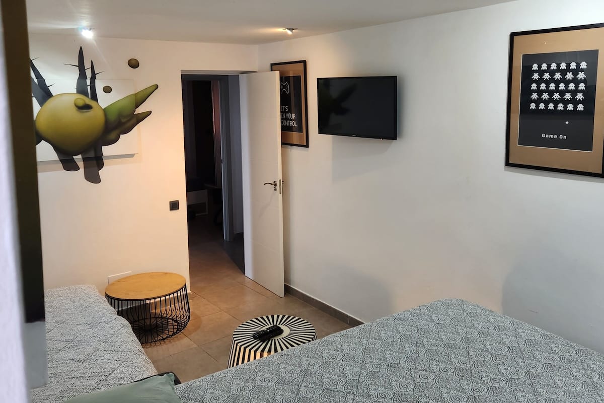 Un dormitorio moderno con cama, televisor y una obra de arte en la pared.