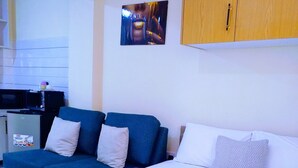 A hotel room with a bed, a blue sofa, and a small kitchenette.