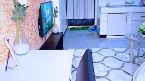 A living room with a TV, a dining table, and a kitchen area.