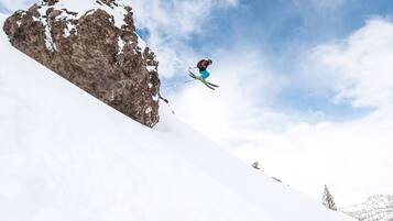 A skier mid-air performing a jump over a snow-covered slope.