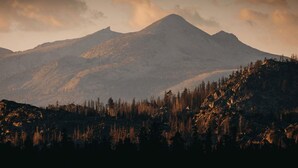 Un paysage de montagne avec un sommet imposant, des pentes boisées et un ciel dégagé.
