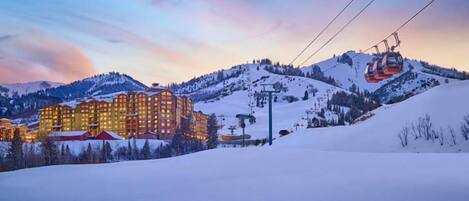 A snow-covered mountain with a ski lift and a hotel in the background.