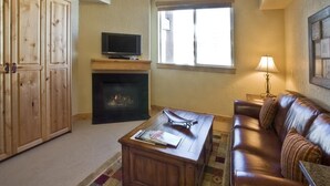 Un salon avec une cheminée, un téléviseur, un canapé en cuir et une table basse.