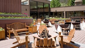 An outdoor patio with wooden furniture, including Adirondack chairs and tables, and a fire pit. - Spacious + Modern Mountain Room (Keystone)