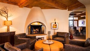 Una sala de estar acogedora con sofás de cuero, una mesa redonda de centro, una chimenea y un comedor visible a través de un arco.