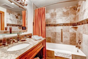 Un baño con tocador doble lavamanos, bañera, ducha con cabezal de ducha manual y perchero para toallas.